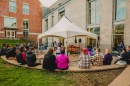 A crowd sits in a semi circle around a small stage with two performers